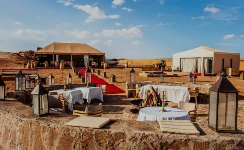 A desert scene featuring tables and chairs, evoking the ambiance of the villes impériales Maroc.