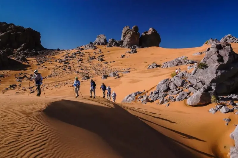 Randonnée dans le désert du Sahara, avec des dunes de sable et un ciel bleu éclatant au-dessus. trek desert maroc