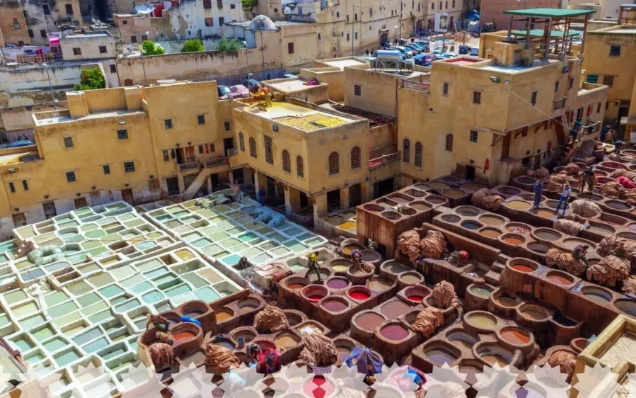 A bustling Moroccan city scene with people carrying pots, showcasing the vibrant life of the imperial cities of Morocco.