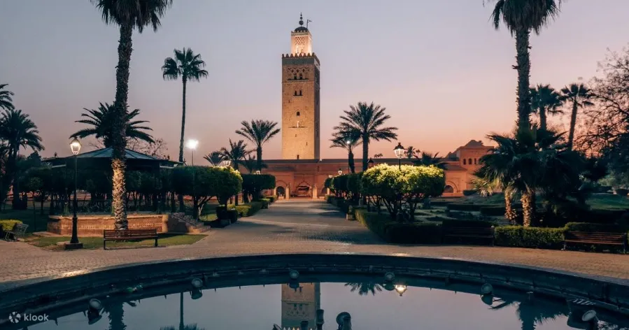Coucher de soleil au centre d'une cour, entouré de palmiers, évoquant une ambiance paisible. Circuit Maroc 10 jours.