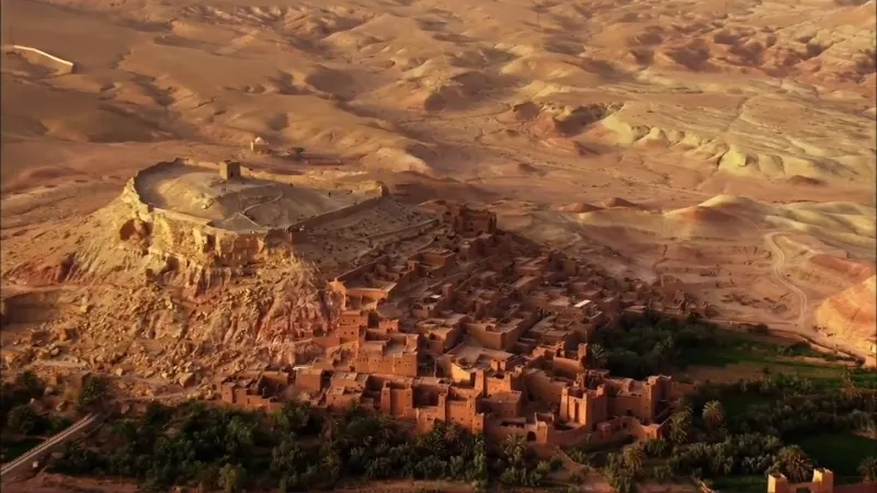 Vue aérienne du désert et des ruines d'une ancienne ville près de Marrakech, avec des paysages arides et historiques.