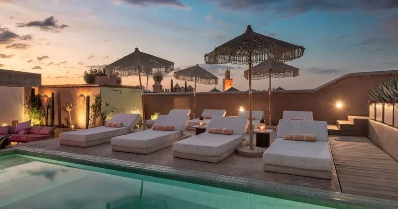 La piscine du riad à Marrakech, Maroc Séjour, entourée de murs ornés et de plantes luxuriantes.