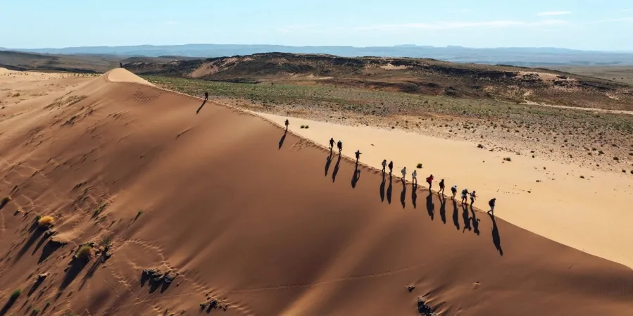 Des personnes marchent le long d'une dune de sable dans le désert marocain.