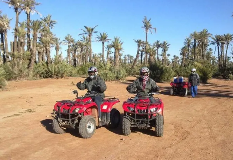 Deux personnes conduisant des quads dans le désert, entourées de palmiers à Quad Palmeraie Marrakech.