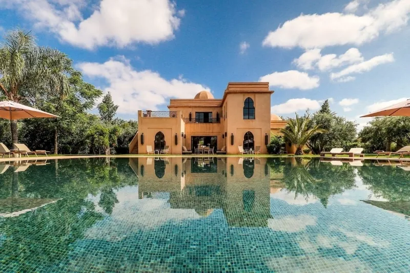 Villa entourée de verdure, avec de l'herbe luxuriante et des arbres, lors d'un séjour au Maroc.