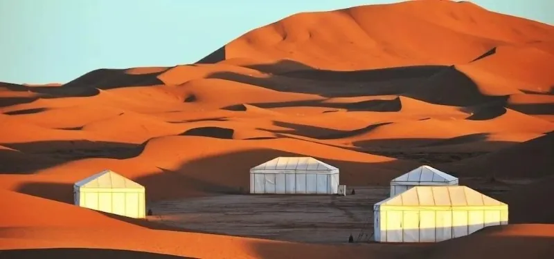 Un paysage désertique à M'hamid Morocco, avec des tentes et des dunes de sable sous un ciel clair.